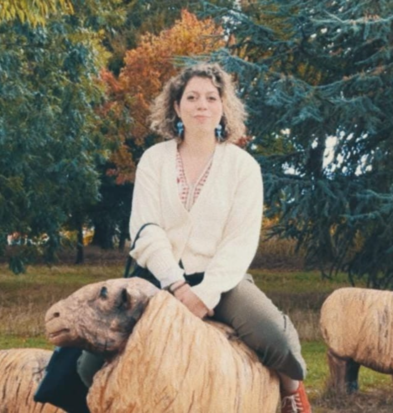Film photo of Marianna Madriz on top of wooden sheep in the woods