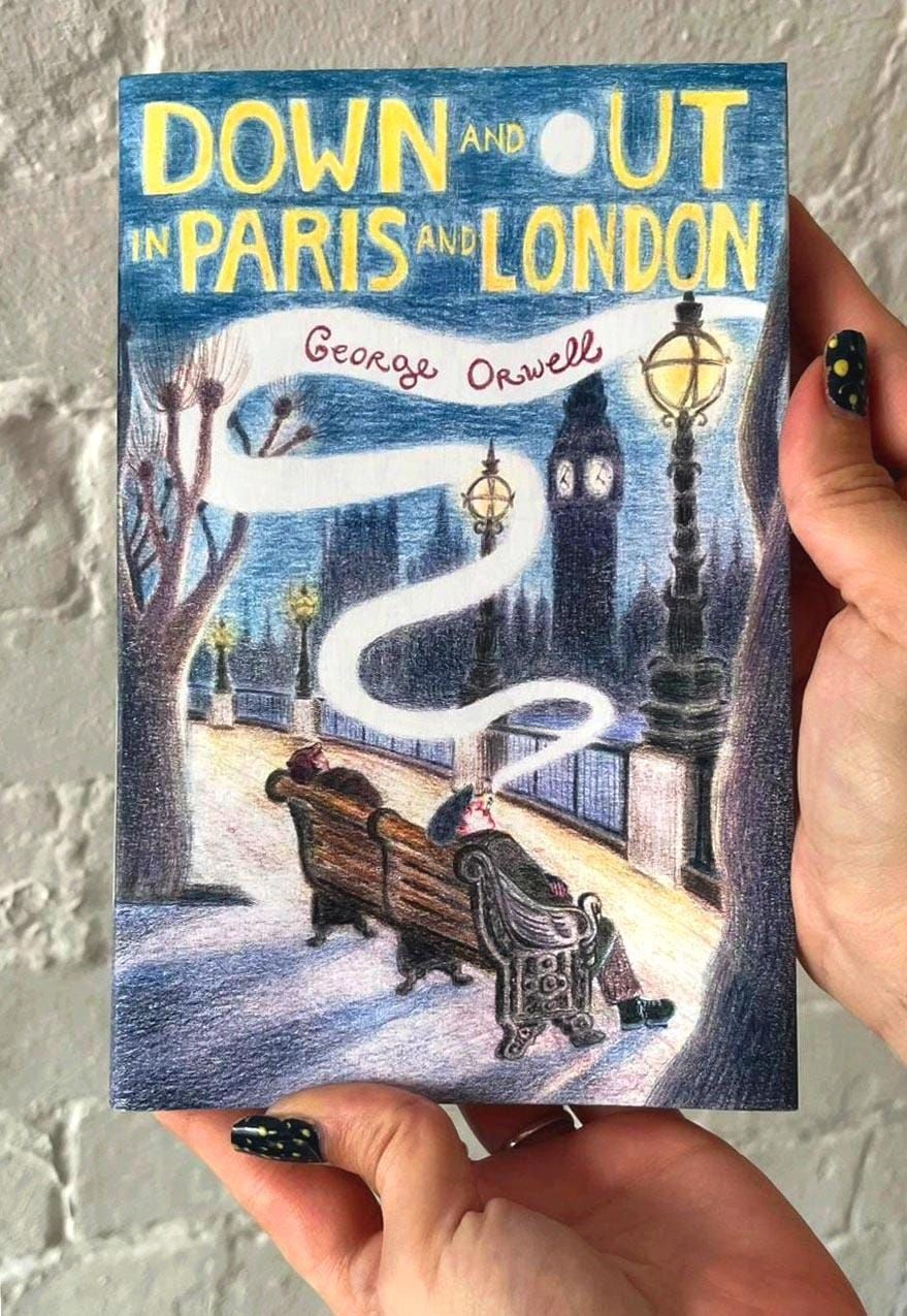 Printed illustrated cover of Down and Out in Paris and London by George Orwell, photographed against white brick wall.