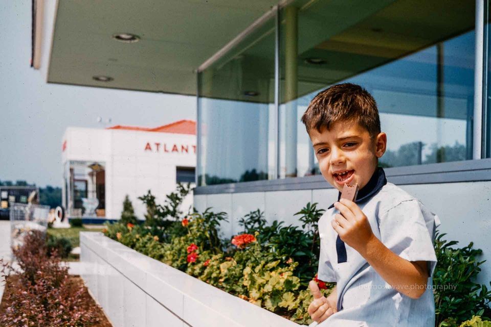 Boy eating a candy bar in front of a modern restaurant.