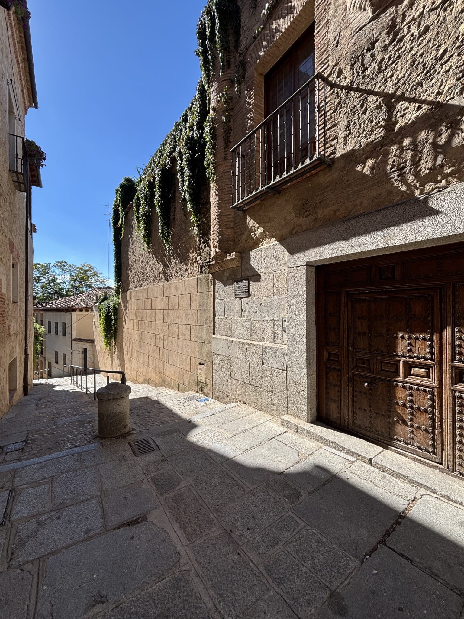 Sunlit steps and stone façades on Calle Grabador Espinosa in Segovia.