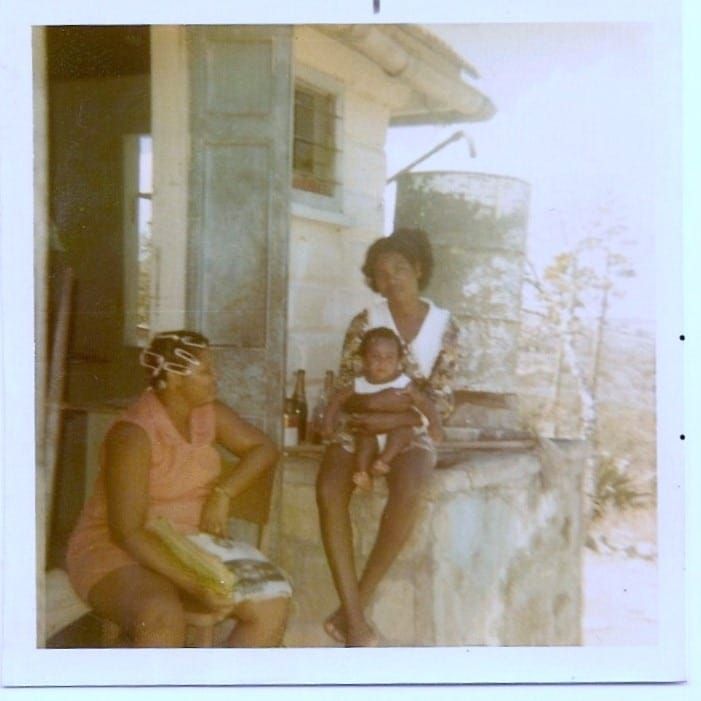 Baby and two women sitting posing for photo.