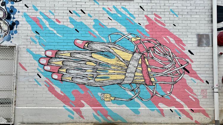 Graffiti art ib a white brick wall. Hand has no skin and computer wires replacing blood vessels.