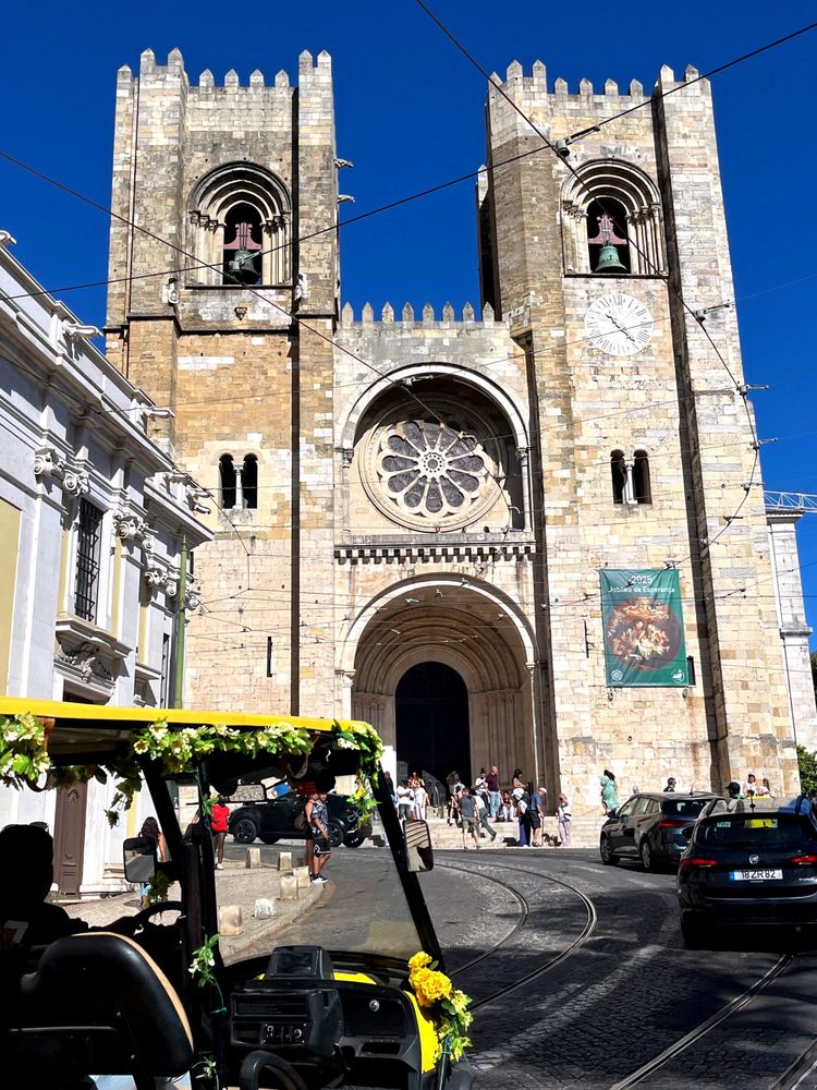 Yellow rickshaw on road in front of church in Lisbon, Portugal
