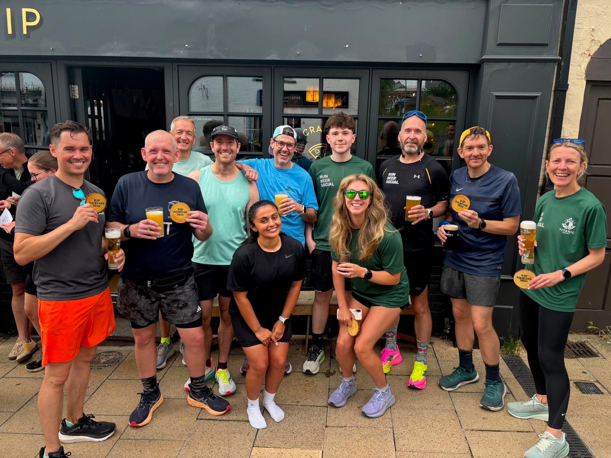 A group of people in running gear, posing outside of the WIP pub, Lichfield, UK