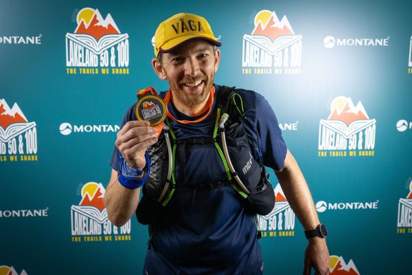 Jon Hickman (me) smiling and holding a Lakeland 50 medal, 1am-ish on 27th July 2025