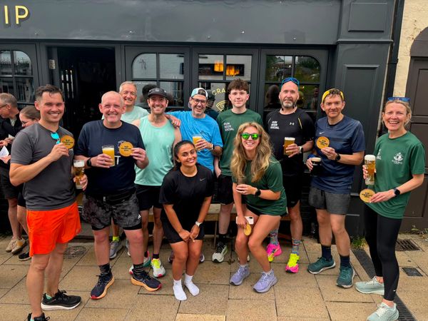 A group of people in running gear, posing outside of the WIP pub, Lichfield, UK