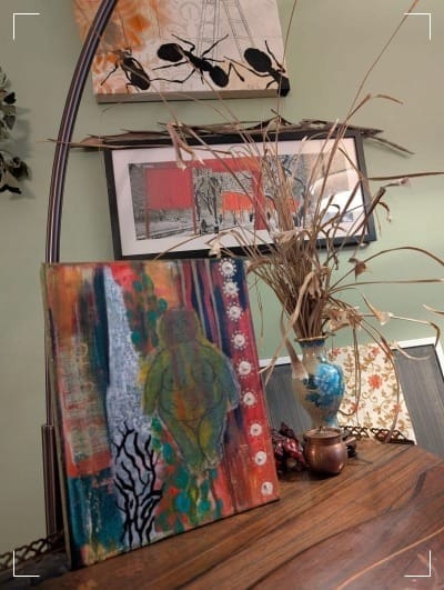 Colorful mixed-media painting of an archaic goddess icon on a wooden table.