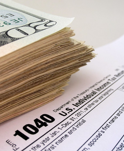 The top of a page that says 1040, US Individual Income Tax Return, with a large stack of cash next to it