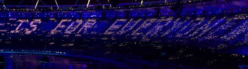 A photo of a darkened stadium, with the words 'is for everyone' visible as lit up seats in the crowd.