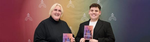 Kestral Gaian and Tobie Donovan stand against a rainbow background.