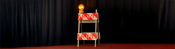 A US-style construction barrier with a yellow warning light on top, with the word HOPE in capital letters written across it.