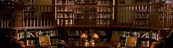 A gothic library with wood railings and stacks of books, from the fictional TV series Buffy The Vampire Slayer