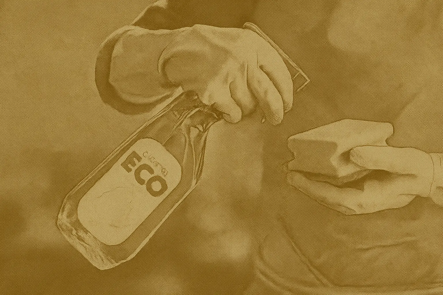 Person wearing rubber gloves cleaning with a reusable sponge and a bottle labeled