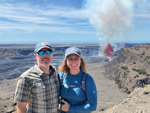 Jason and Kat standing in front of an erupting volcano.