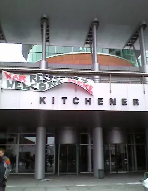 A banner hanging from the top of Kitchener City Hall that states "war resisters welcome here"