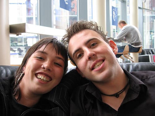 Two white people with dark hair posing for a selfie in a coffee shop.