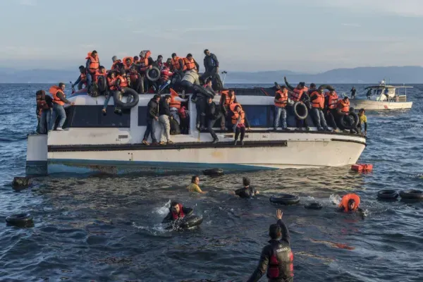 Refugees on a boat, many in the sea around it.