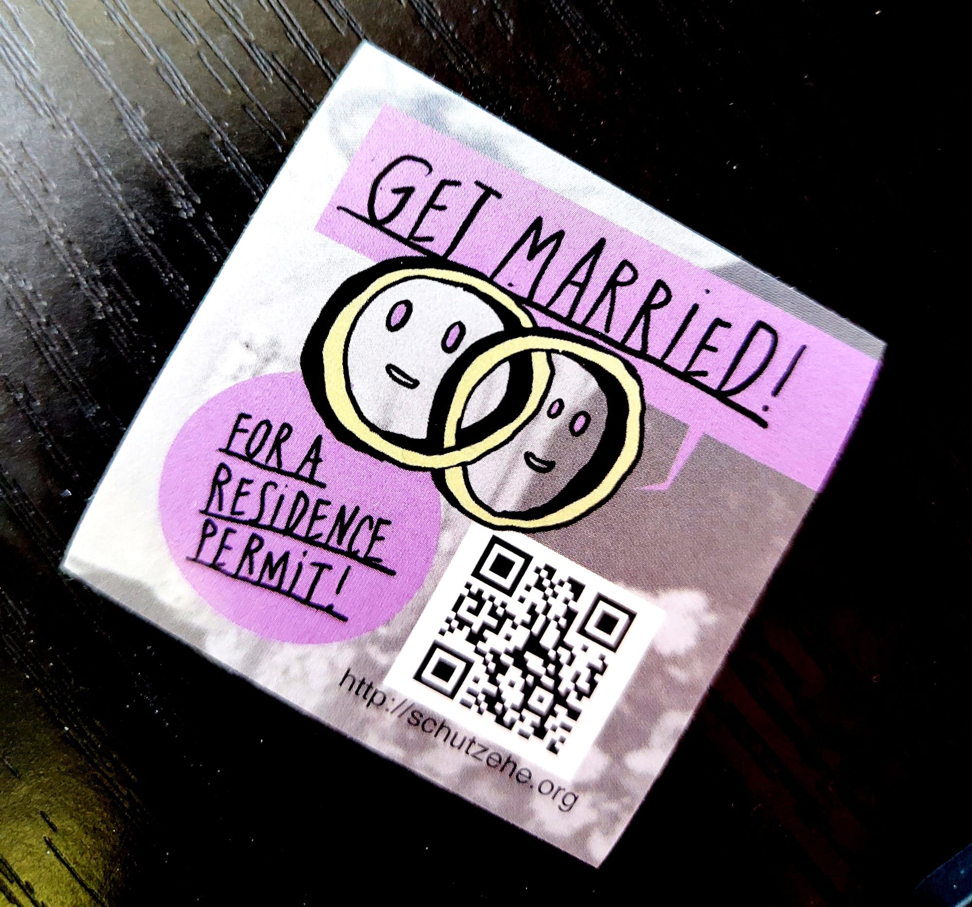 A sticker with two rings on it and the text "Get Married! For a residence permit!"