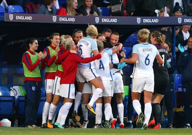 The (mostly white) England women make a point of celebrating with Mark Sampson on the touchline after the allegations.