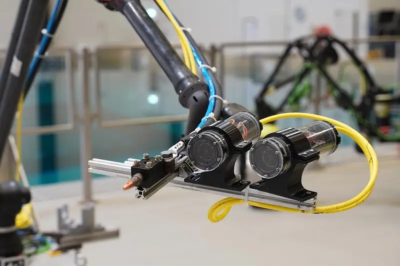 Welding torch and stereo cameras on the robot end effector during test preparations in the Maritime Exploration Hall at DFKI Bremen.