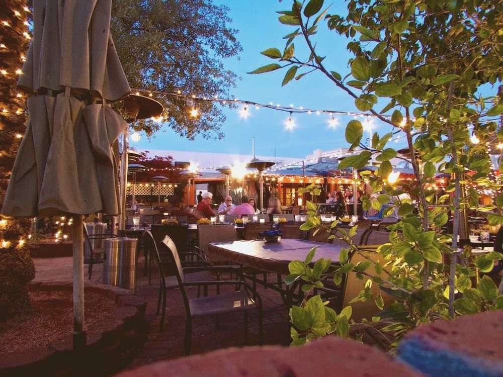of a vacant desert-adobe courtyard patio at dusk, string lights unlit, terracotta walls, no people