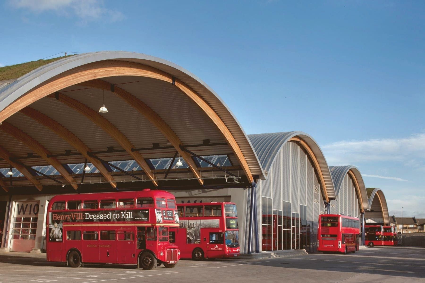 of a row of open garage doors revealing classic and sports cars, desert landscape visible in the background at midday