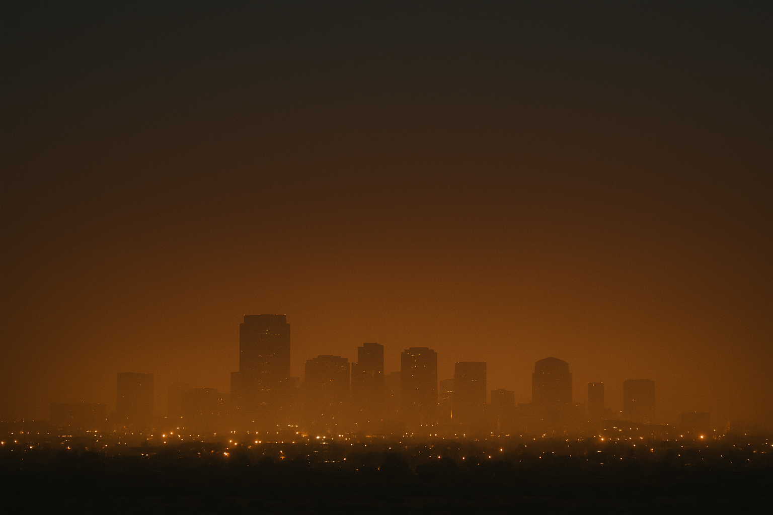 of a hazy predawn Phoenix skyline seen from a distance, orange-brown particulate haze visible against a dark sky, no people