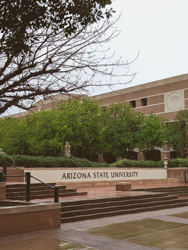 Wide aerial view of a large university campus at midday, desert landscape visible at the edges, no people, no text