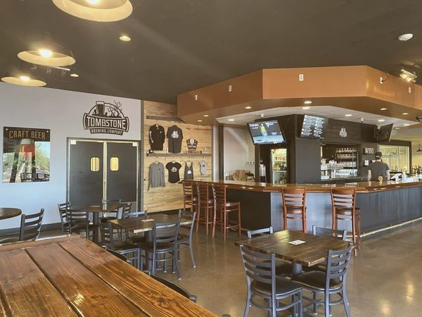 of a crowded bar interior at night, television screens glowing with a soccer match, patrons standing and cheering, no faces i