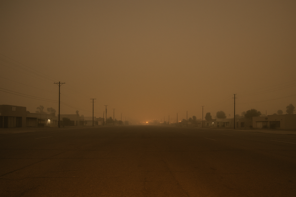 of a hazy desert sky over a flat urban landscape at night, faint orange glow on the horizon, no people