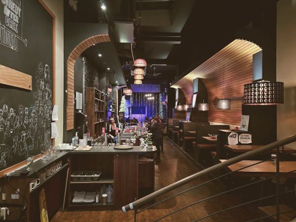 Empty coffee shop interior at dusk, warm pendant lighting over wooden tables, no people, desert-toned decor