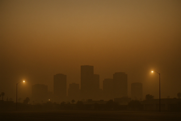 of a hazy desert sky at pre-dawn, orange and brown particulate haze visible over a flat urban horizon, no people, no text