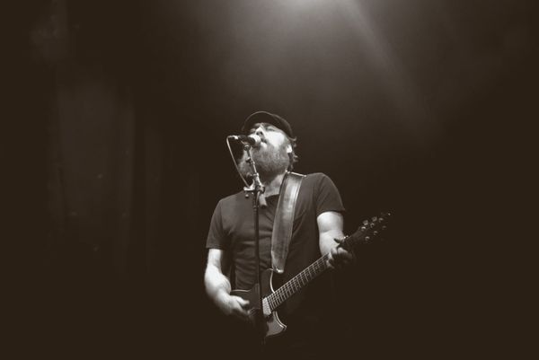 Empty concert hall stage with warm amber stage lighting, microphone stand centered, no people