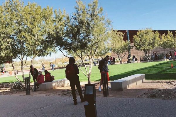 of an empty community college lecture hall at dawn, rows of chairs facing a blank whiteboard, warm desert light through tall