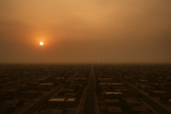 of a hazy desert sky at dusk over a flat urban landscape, orange and brown tones, no people, no text