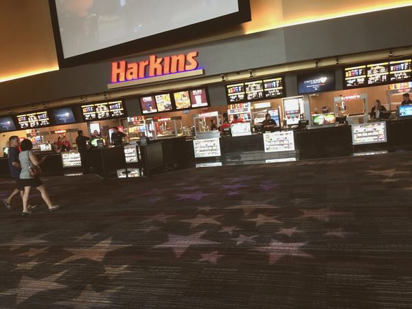 Empty movie theater auditorium with rows of dark seats, dramatic overhead lighting, no people