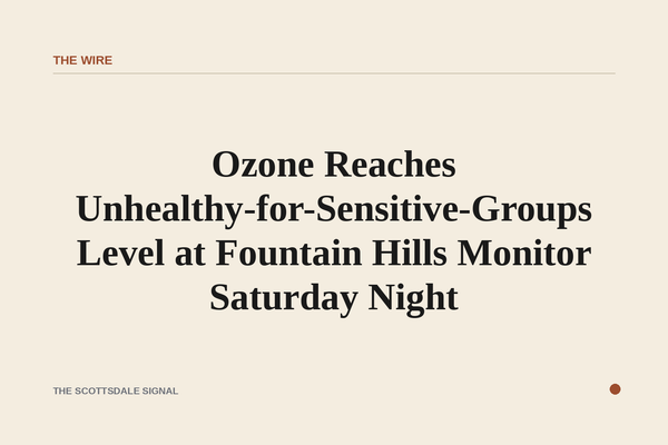 of a hazy desert sky at dusk over low desert hills, warm orange light diffused through atmospheric haze, no people