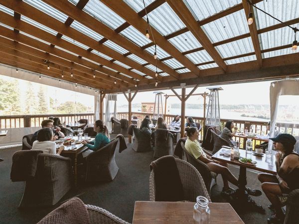 Empty bistro dining room at dusk, white tablecloths, bentwood chairs stacked on tables, warm amber light through a street-fac