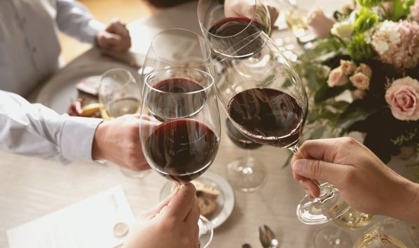 of several wine glasses filled with deep red wine on a wooden tasting table, warm afternoon light, no people