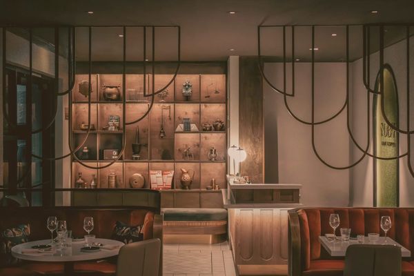 Empty upscale restaurant interior at dusk, warm amber lighting, dark wood tables, no people