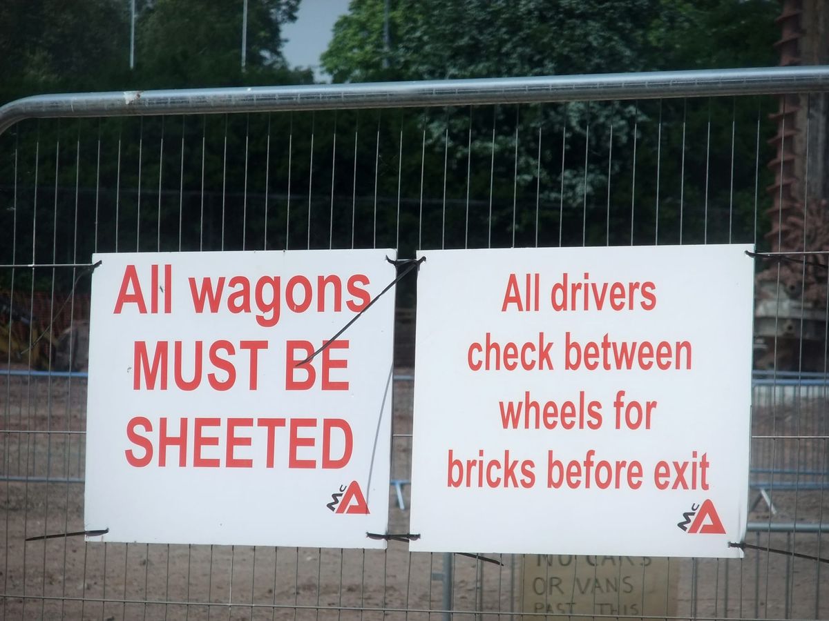 A sign on a fence reading, "All wagons MUST BE SHEETED."