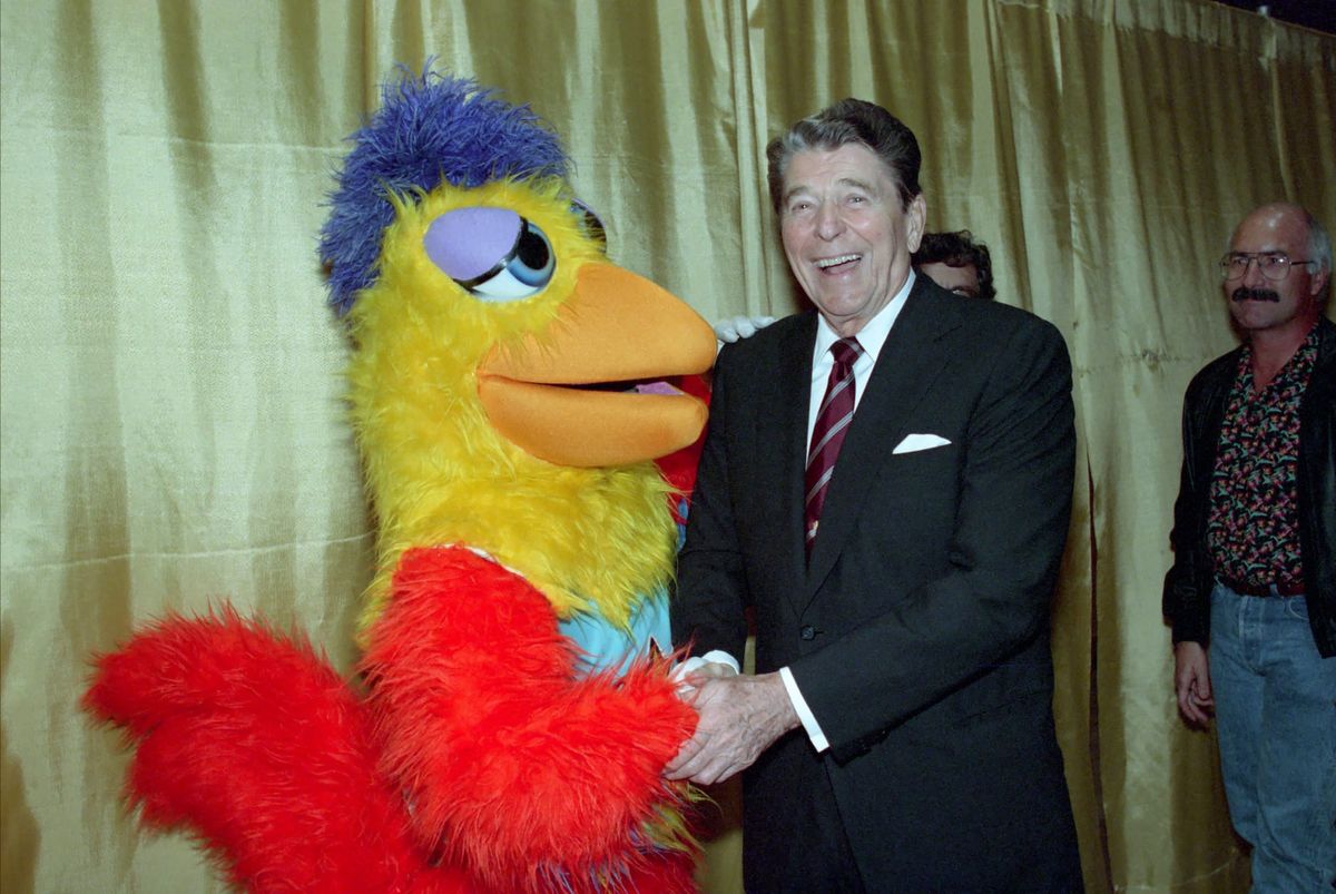 President Reagan shakes hands with a chicken. 