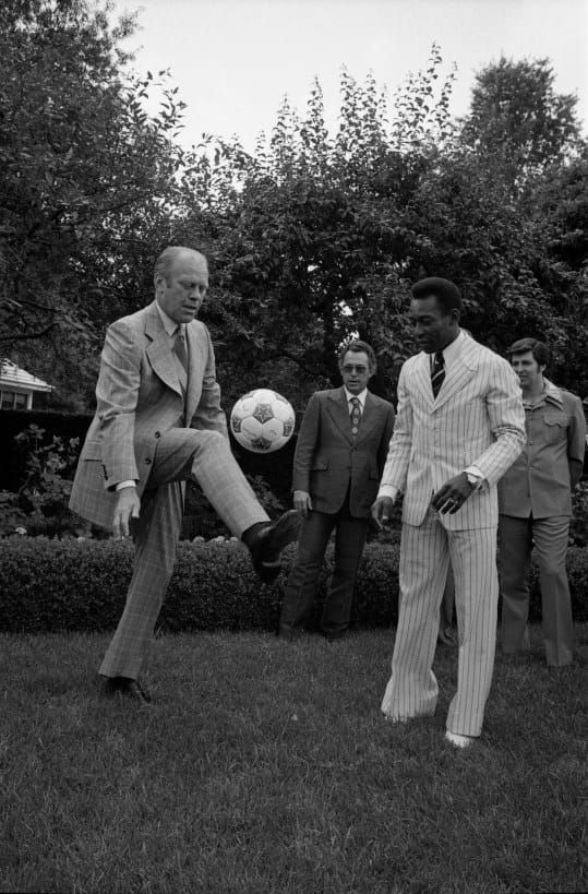 President Ford kicks as soccer ball as Pelé looks on. 