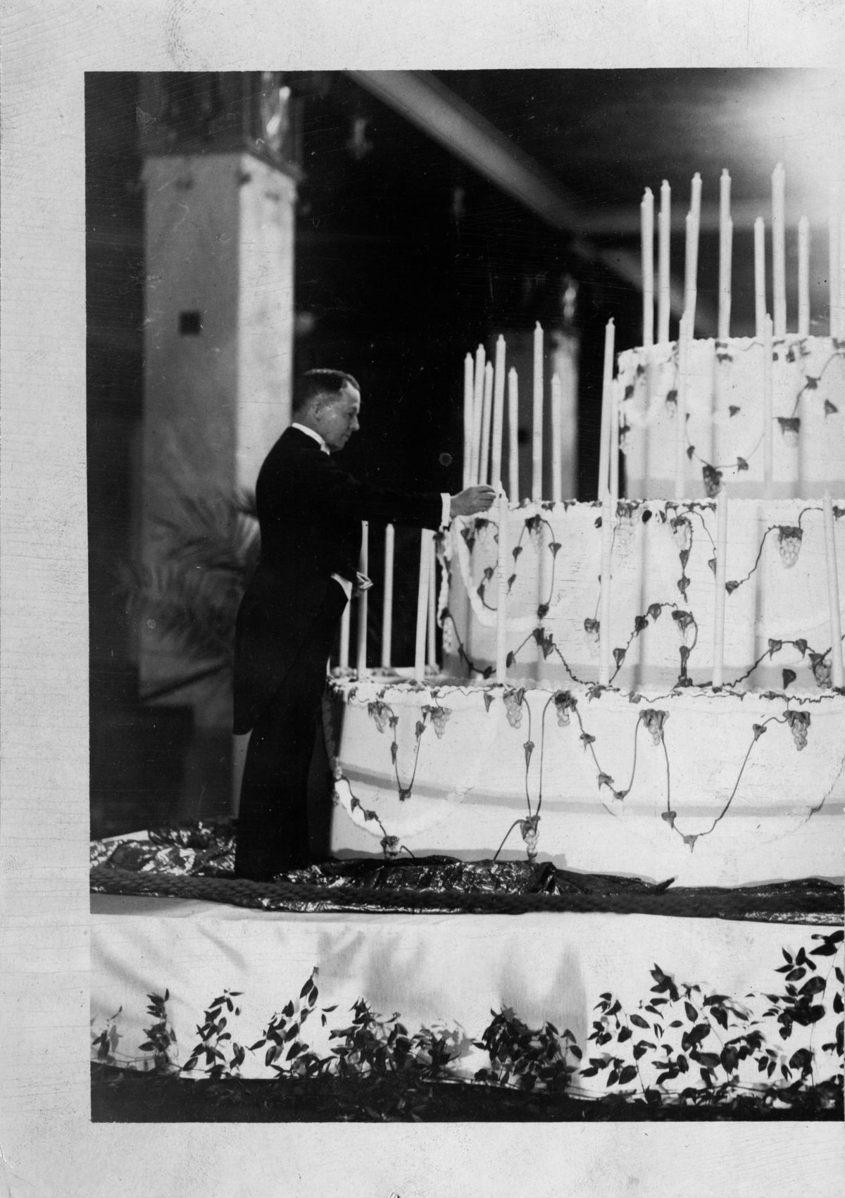 Minneapolis Mayor George Leach lights candles on a sizable cake to celebrate his city's Diamond Jubilee. 