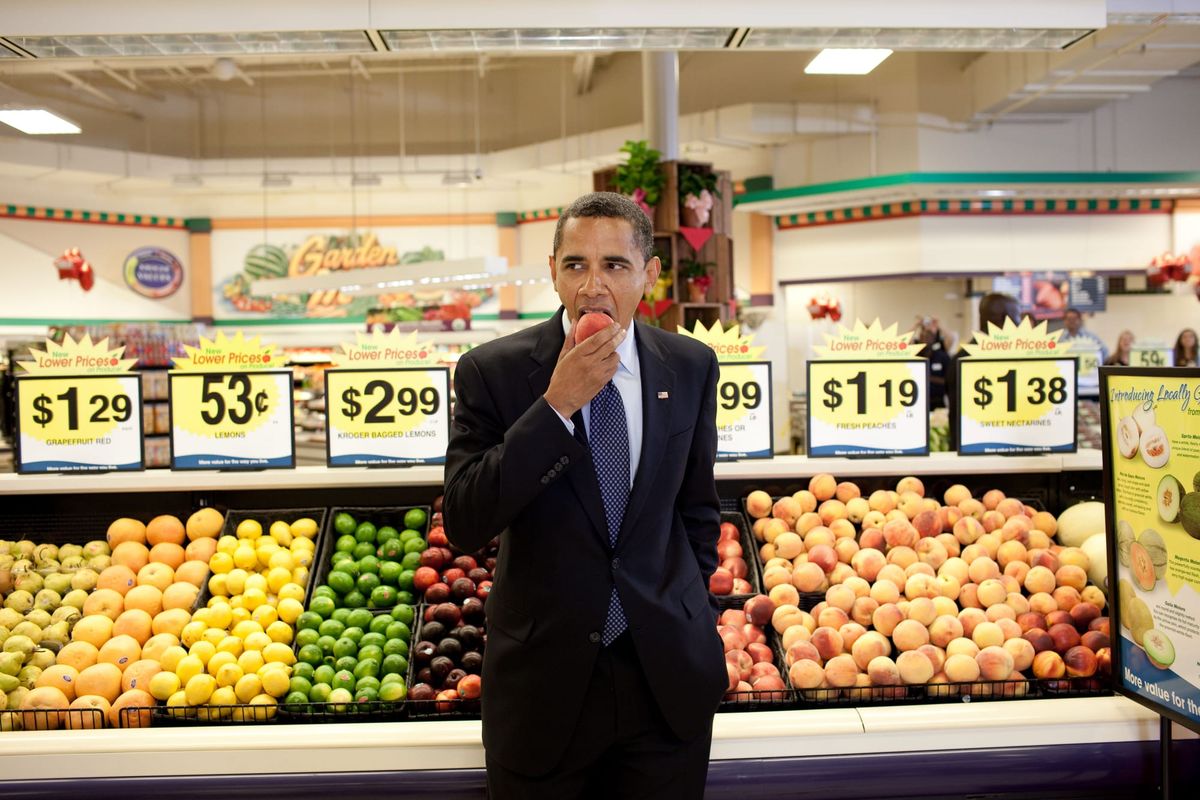 President Obama eats a peach in a grocery store.
