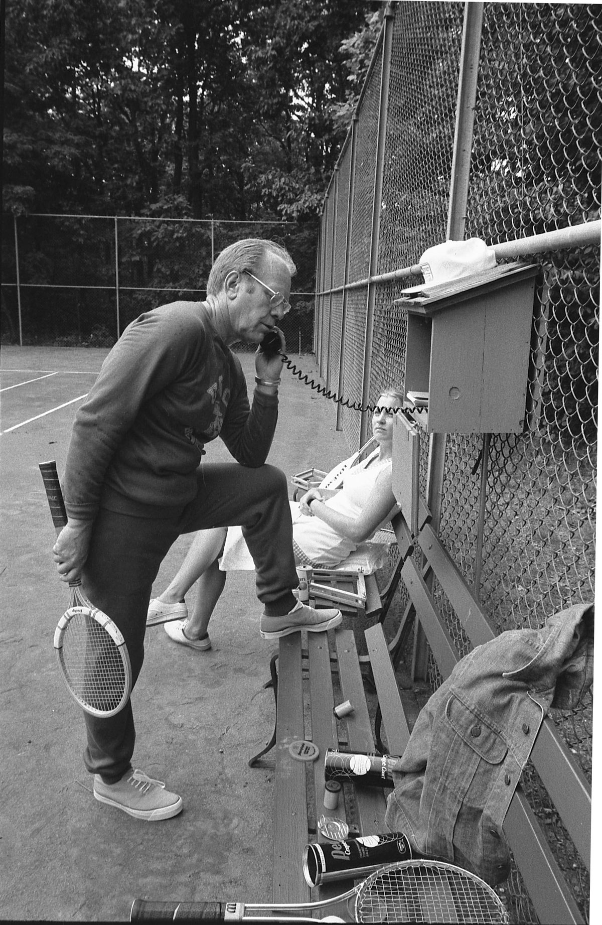 President Gerald Ford holding a tennis racket and taking a call on a rotary phone. 