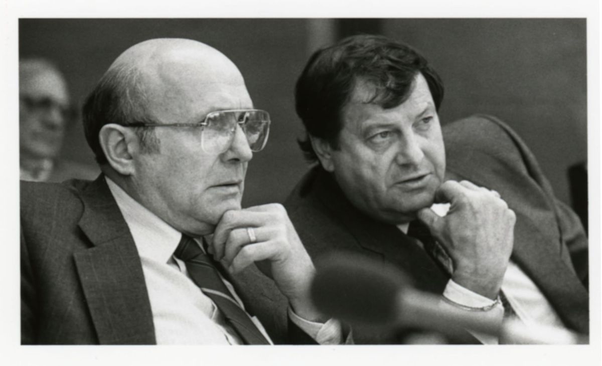 State Senators John Bernhagen + Mel Frederic listening, with hands on their chins, to committee testimony. 