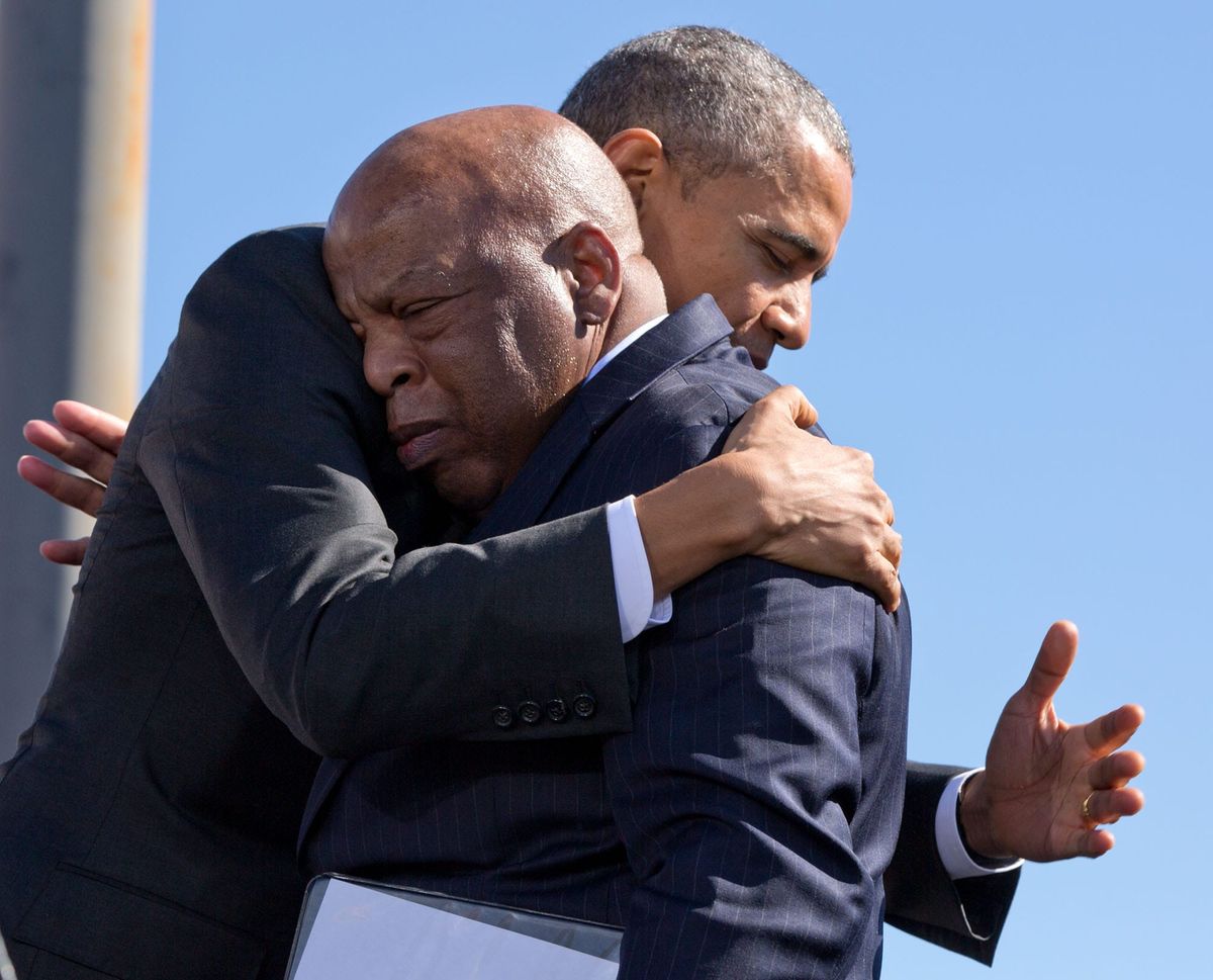 Congressman John Lewis in blue, hugs President Barack Obama in black on a clear day. 
