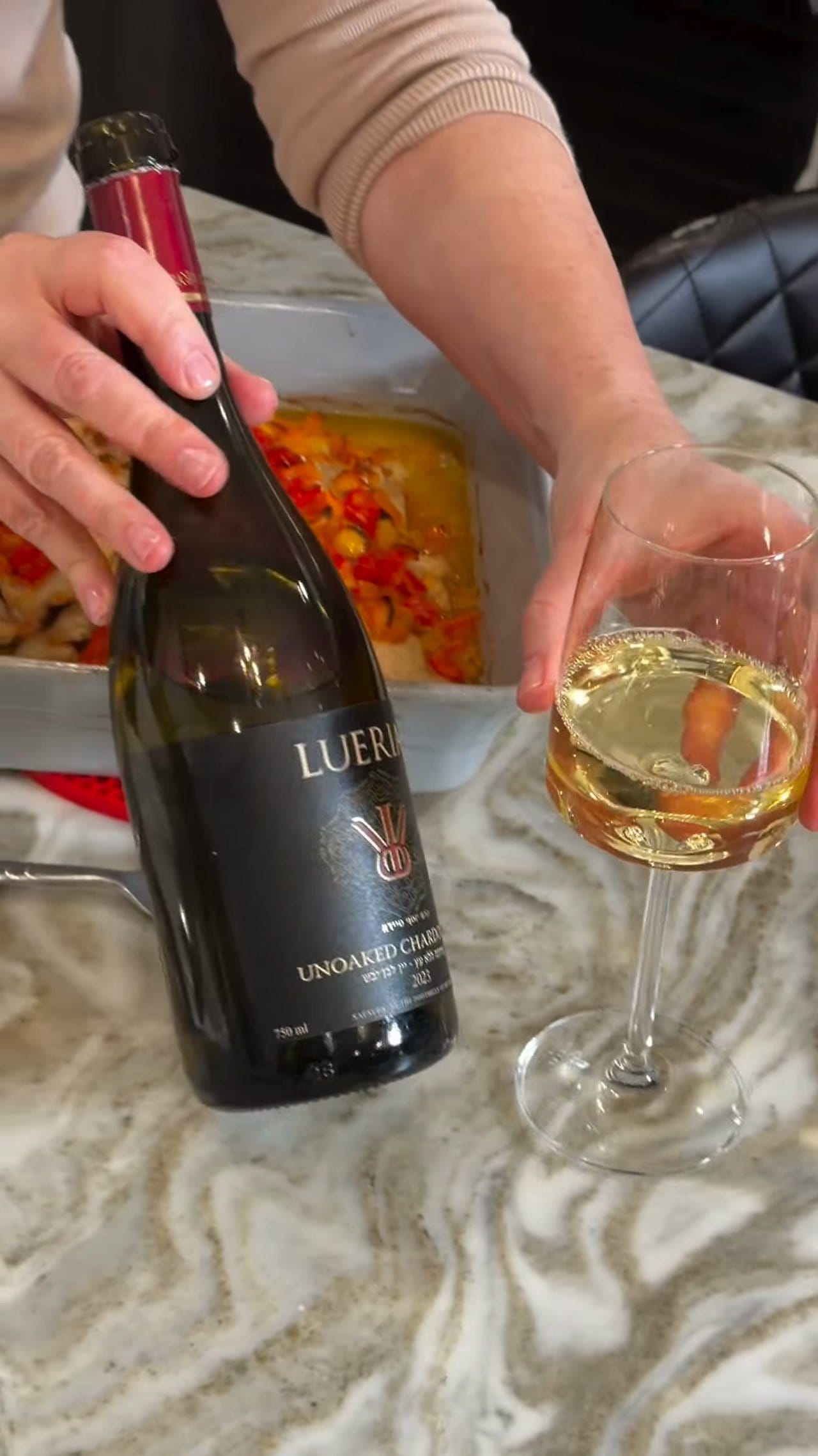 A bottle of Lueria Unoaked Chardonnay and a poured glass beside the baked pepper chicken