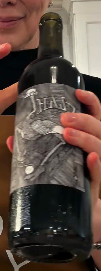 Bottle of Hajdu Grenache with its grey, engraved-style illustrated label, held in Anne's hand